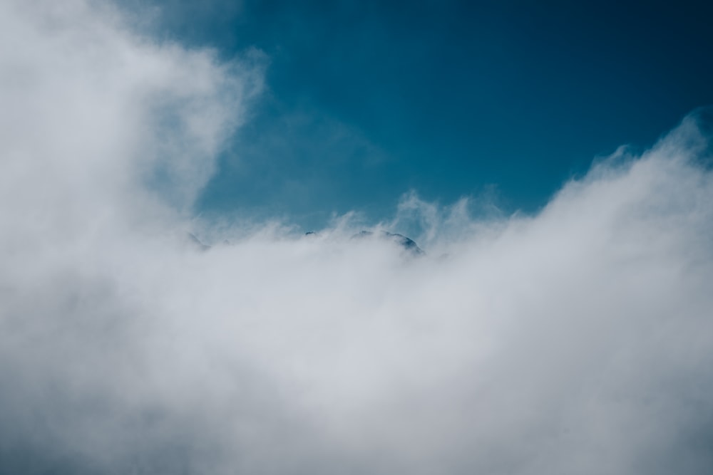 a bird flying through a cloud filled sky