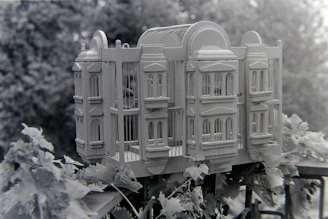 An elegant Sing birdcage with smooth curves and polished wood.