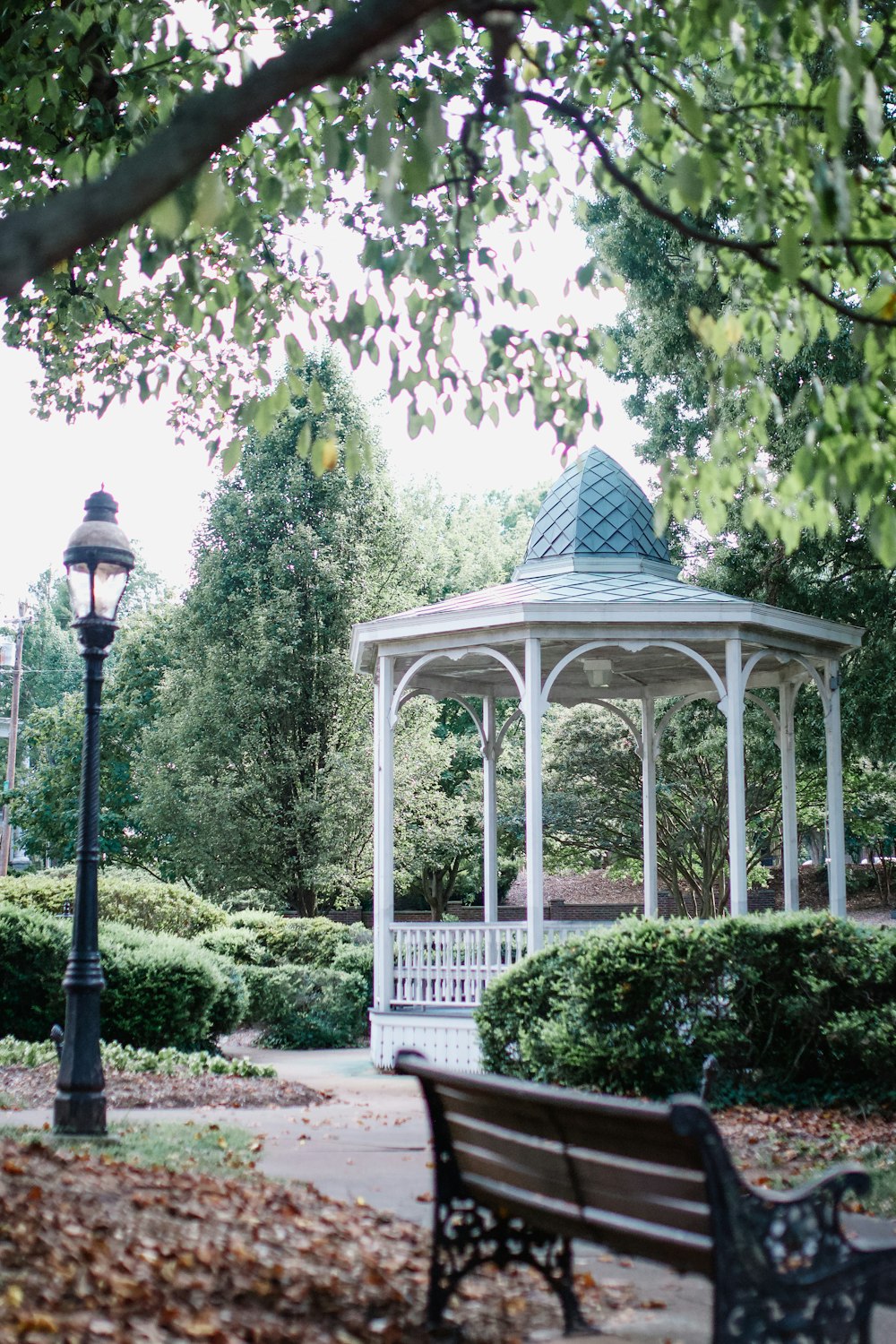 a gazebo in a park surrounded by trees and bushes