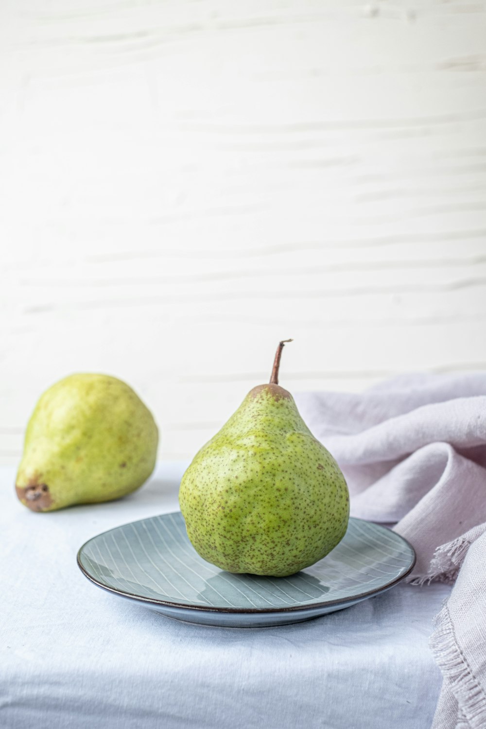 two pears sitting on a plate on a table