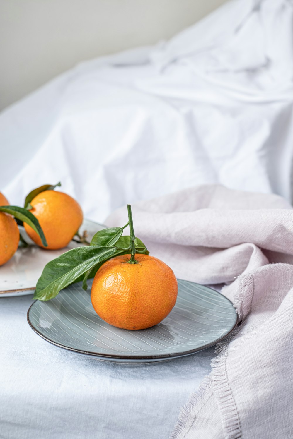 three oranges on a plate on a bed