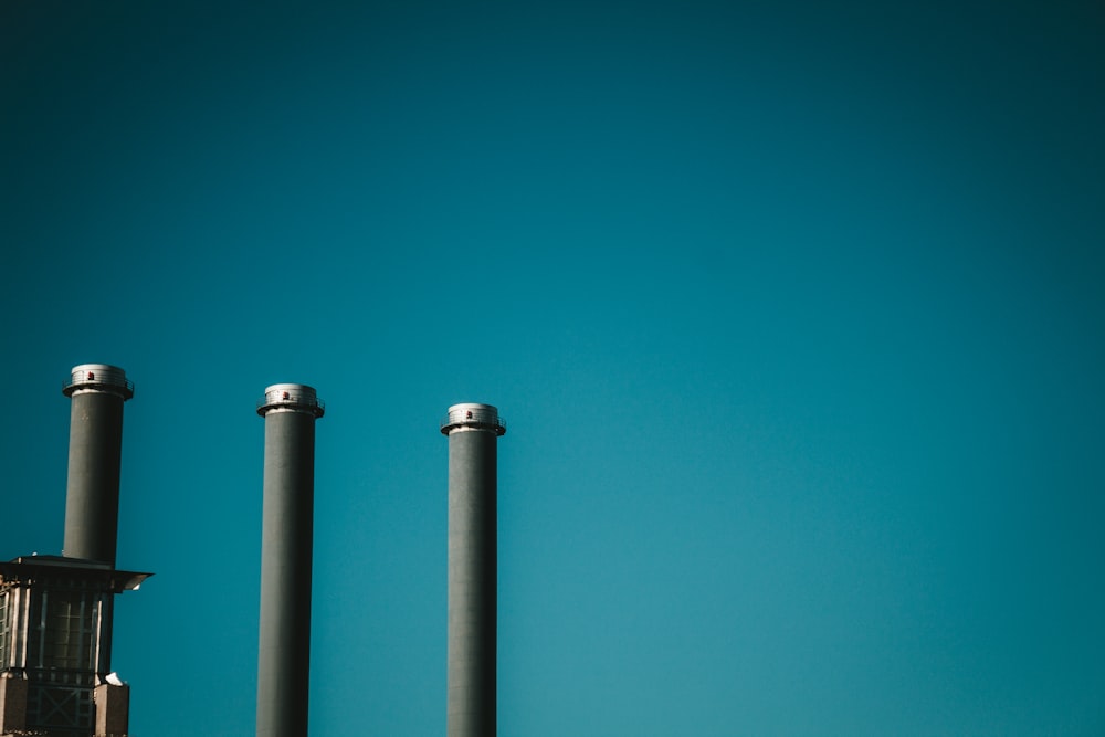 a blue sky with three metal pipes in the foreground