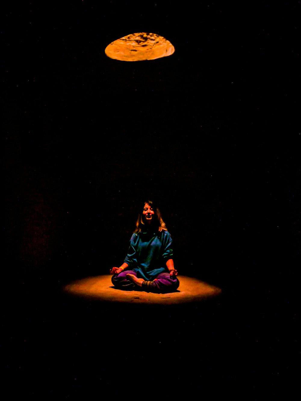 a woman sitting in the middle of a dark room