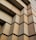 A close-up view of a building facade with a geometric pattern of large rectangular concrete blocks, creating a sense of depth and texture. The pattern consists of staggered, protruding blocks, forming a repetitive, rhythmic design.