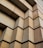 A close-up view of a building facade with a geometric pattern of large rectangular concrete blocks, creating a sense of depth and texture. The pattern consists of staggered, protruding blocks, forming a repetitive, rhythmic design.