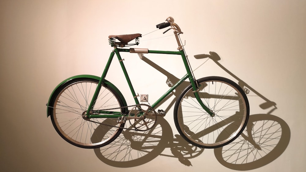 a green bicycle is hanging on a wall