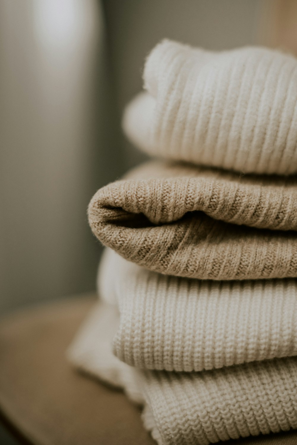 a stack of folded sweaters sitting on top of a table