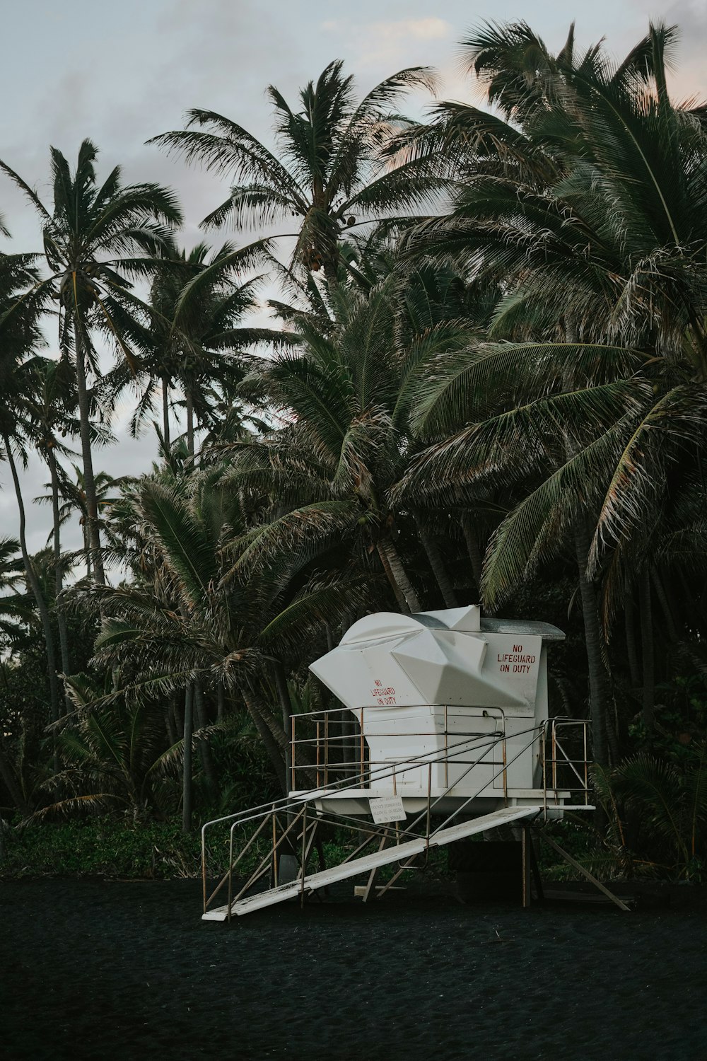 a lifeguard stand on a beach with palm trees in the background