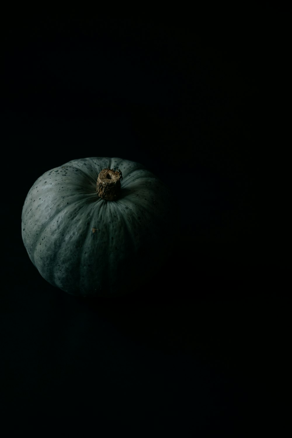 a green pumpkin sitting on top of a black table
