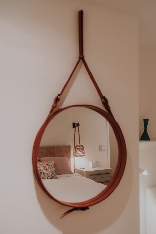 a mirror hanging on a wall above a bed