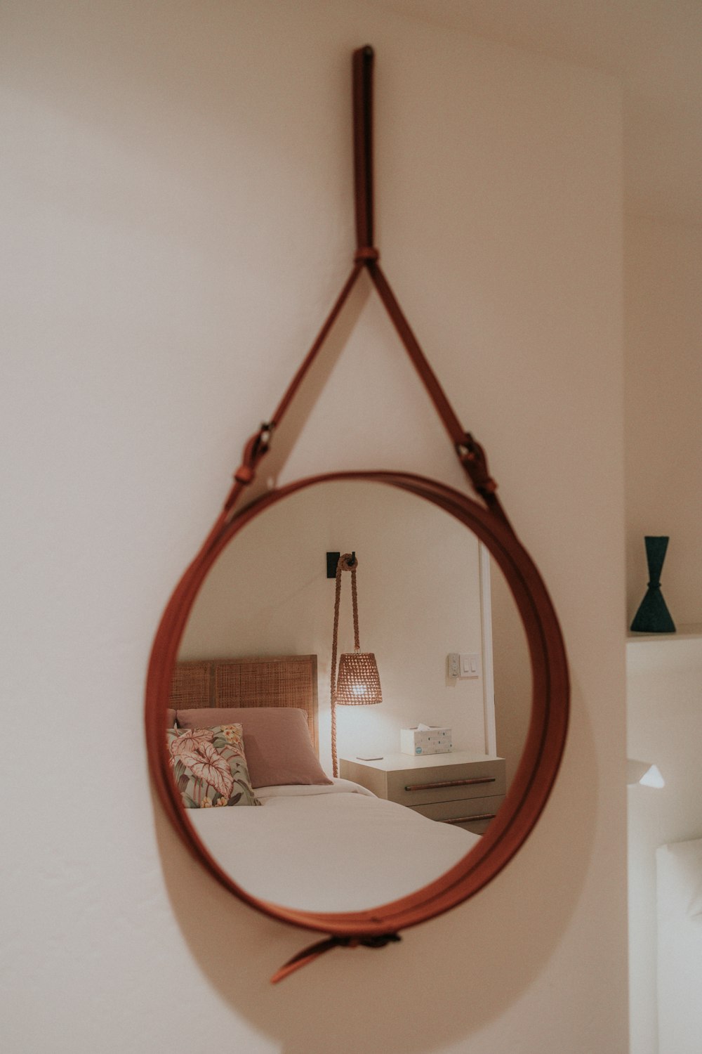 a mirror hanging on a wall above a bed