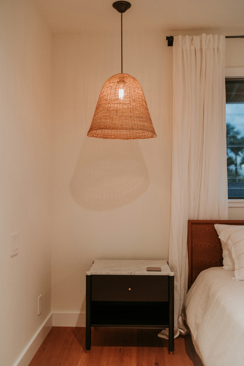 a bedroom with a bed and a lamp hanging from the ceiling