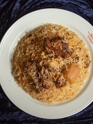 a white plate topped with rice and meat