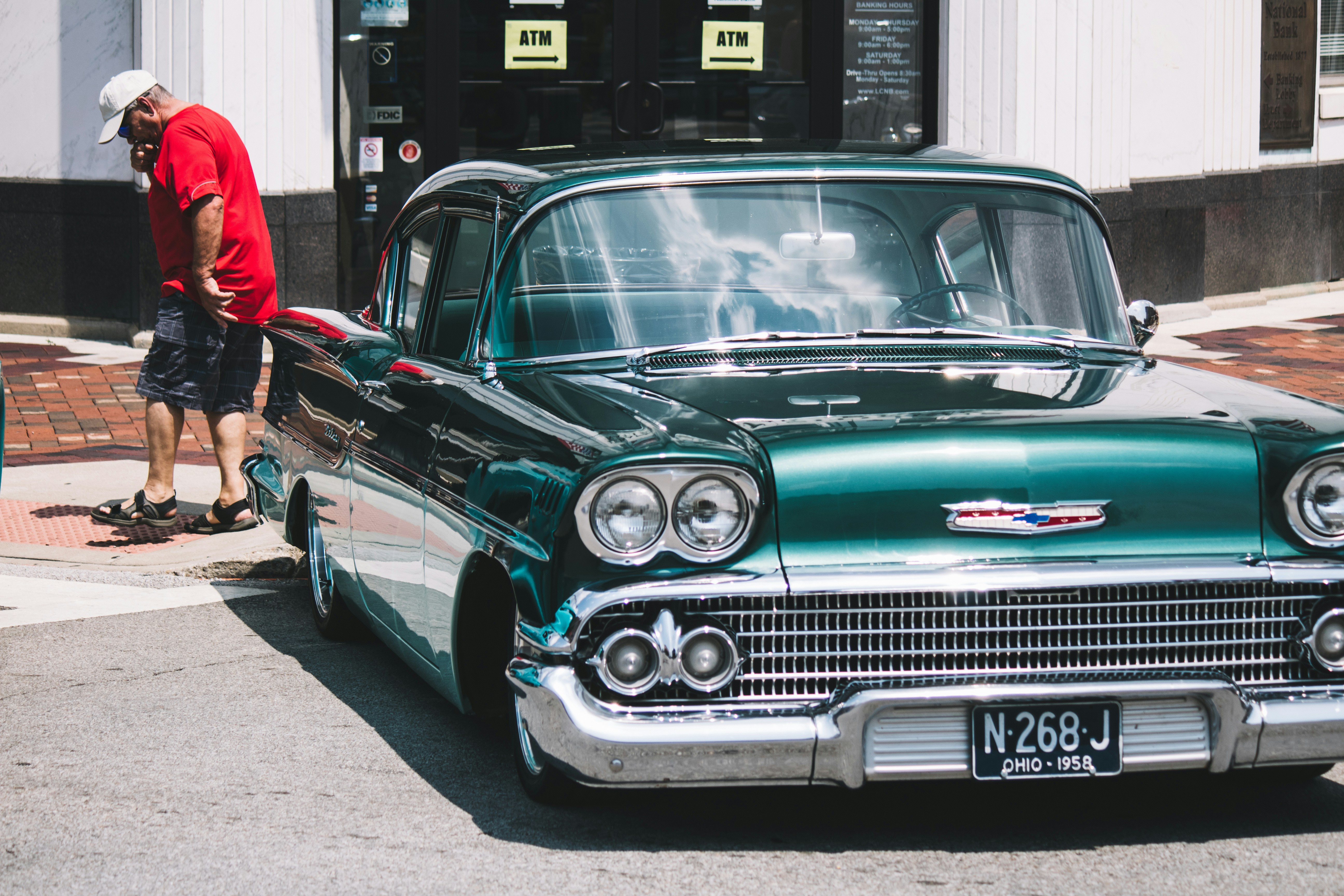 Un homme se tenant à côté d une voiture classique verte reflétant l ambiance urbaine et nostalgique du pays