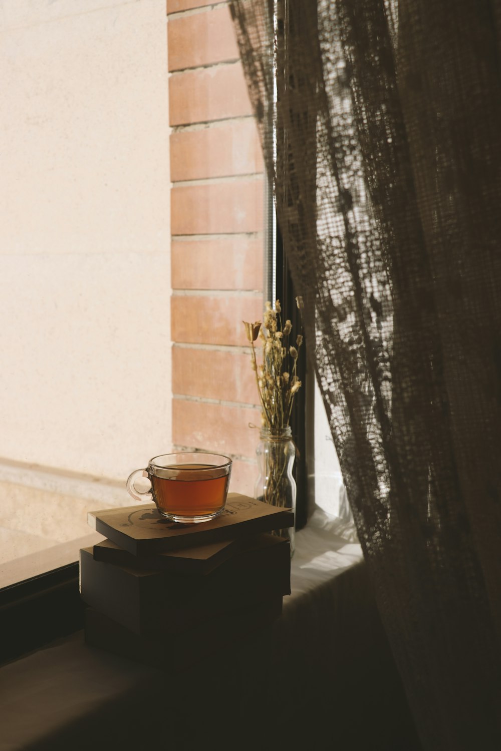 una tazza di tè seduta sopra un tavolo accanto a una finestra