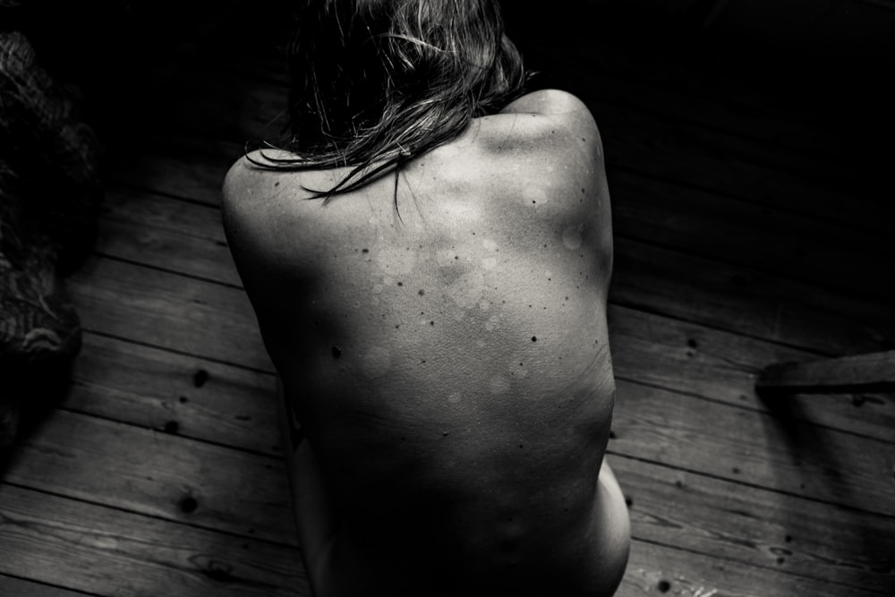 a naked man sitting on a wooden floor