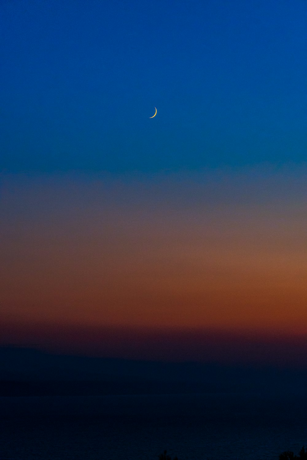 La luna se está poniendo sobre el horizonte del océano