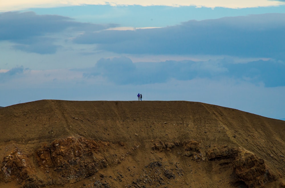 um par de pessoas em pé no topo de uma colina