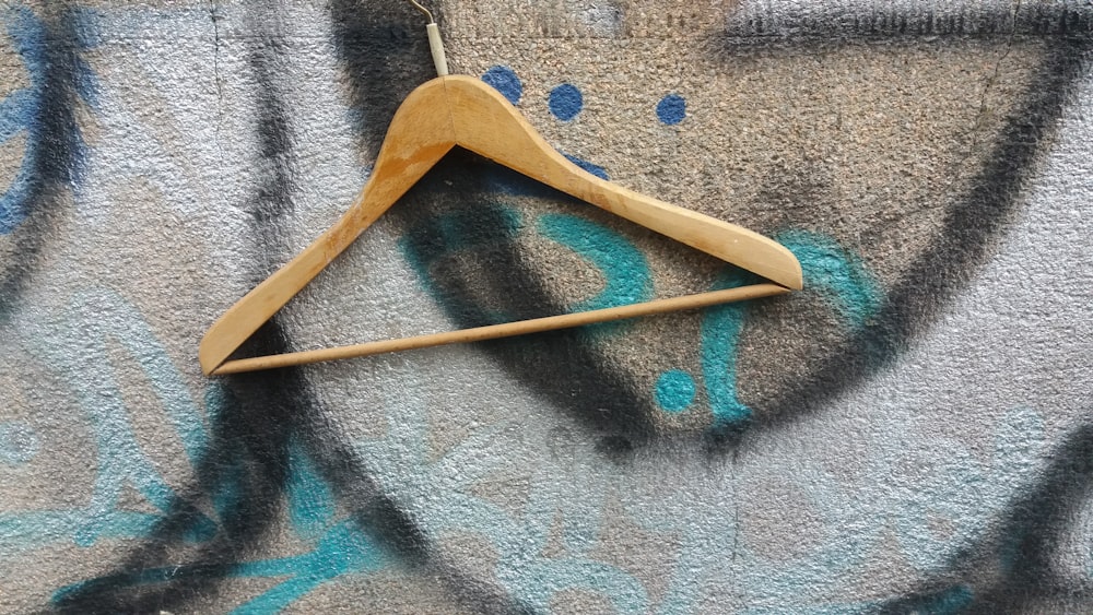 a wooden hanger on a graffiti covered wall