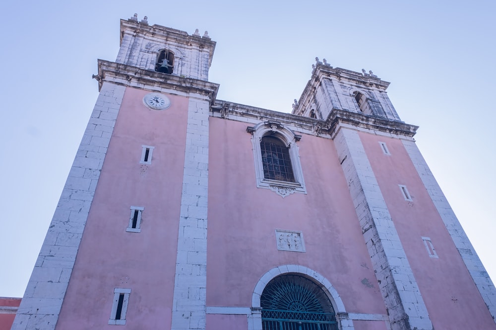 a tall pink building with a clock on it's side