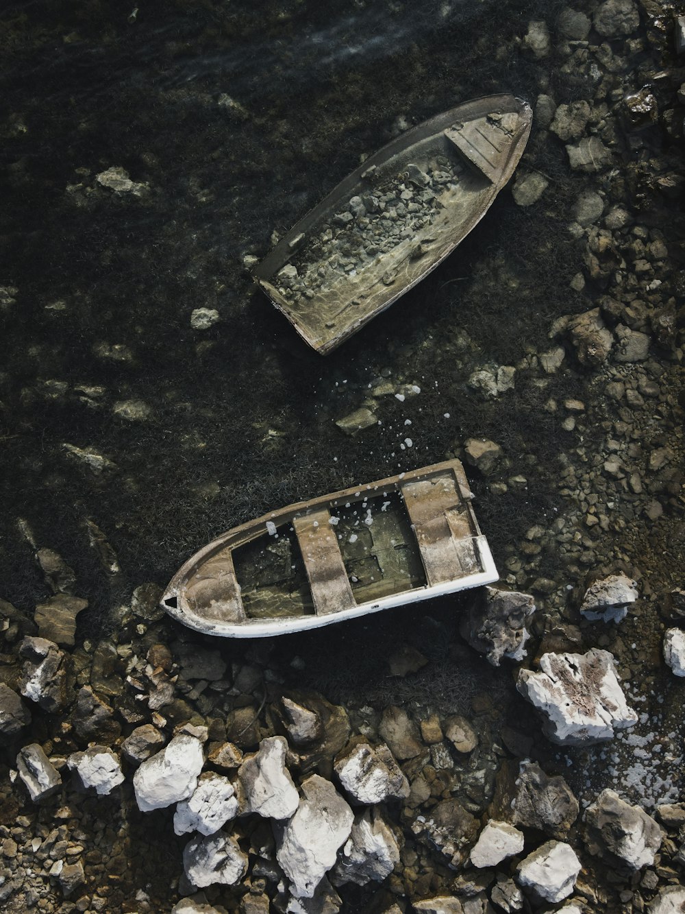 two small boats sitting on top of a rocky beach