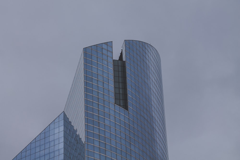 a very tall glass building with a clock on it's side