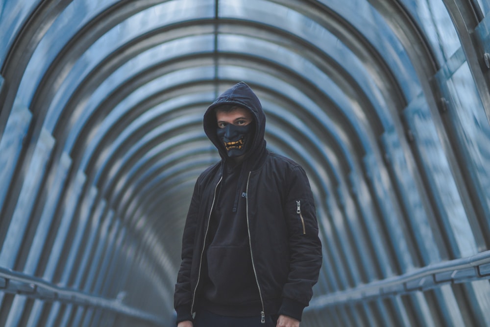 a man wearing a black hoodie and a black mask