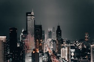 Modern city skyline at night with illuminated skyscrapers and bustling streets.