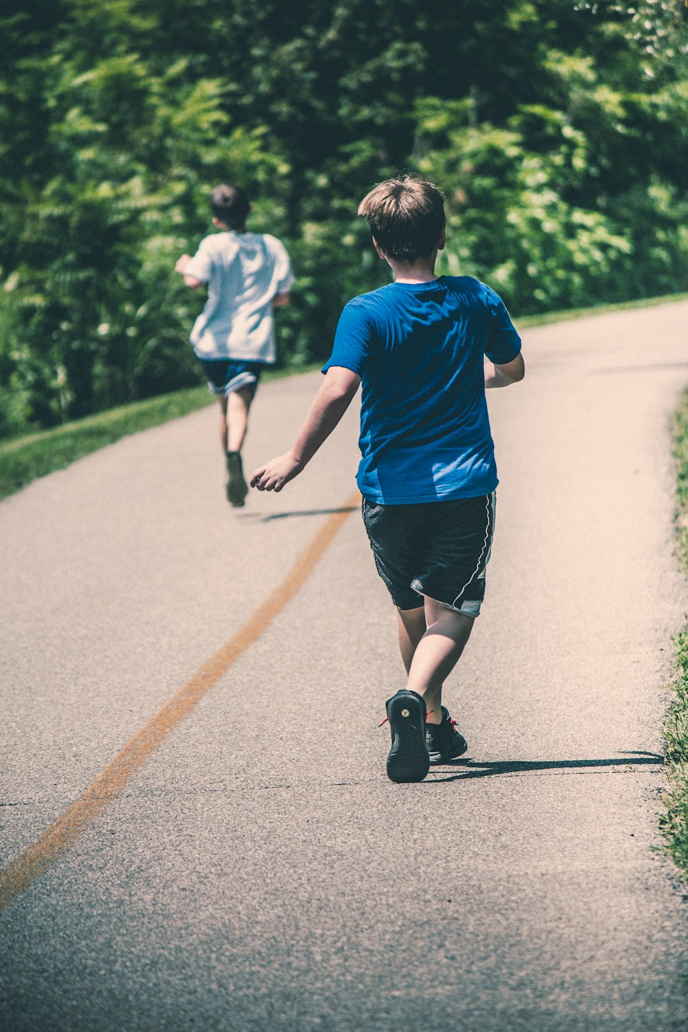 a young boy is running down the road with a skateboard