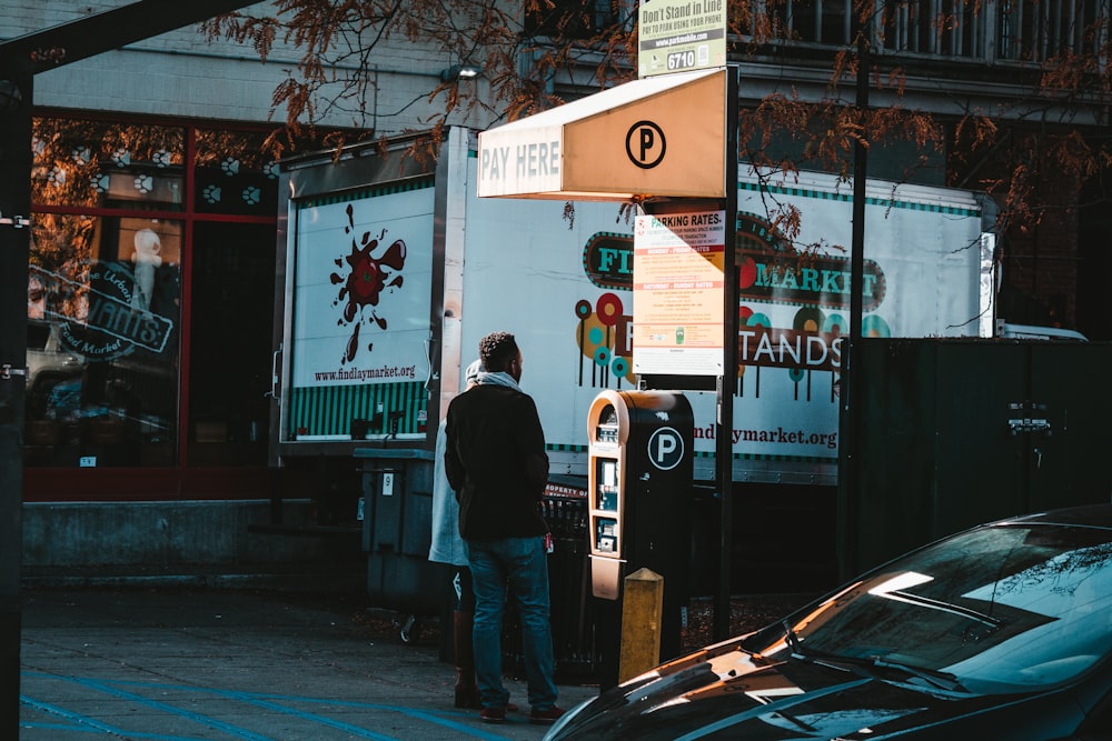 a man standing next to a parking meter