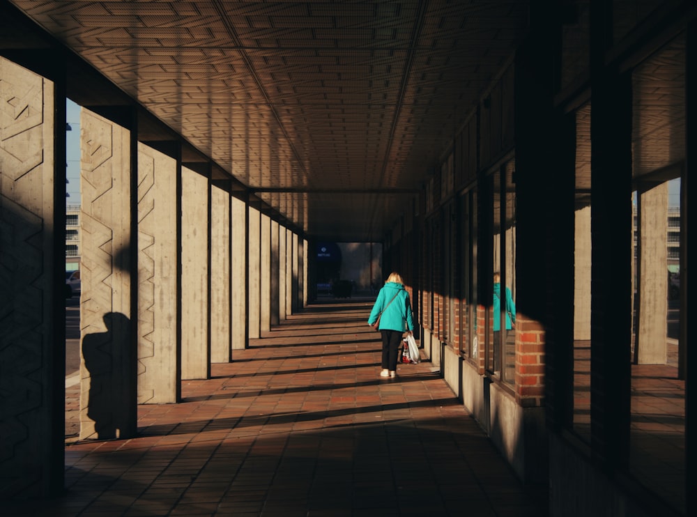 a woman is walking down a long hallway