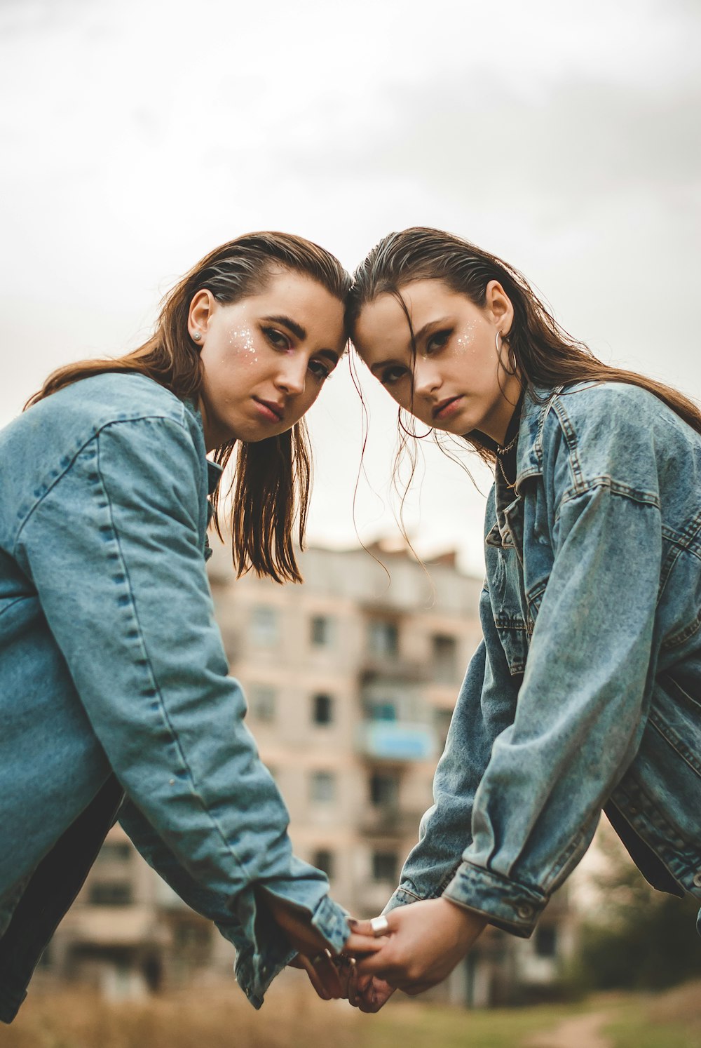 two young women holding hands in front of a building