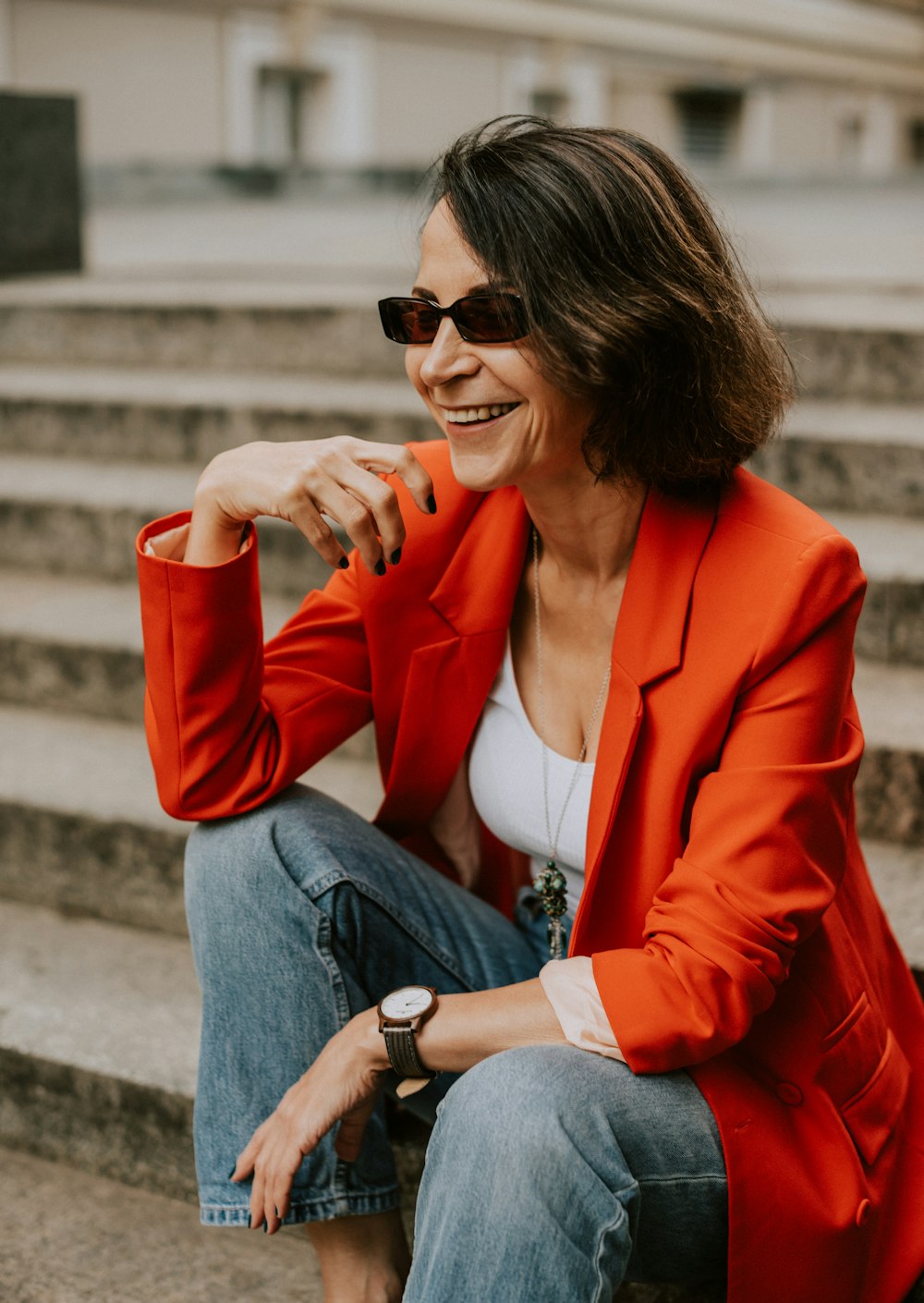 a woman in a red jacket sitting on some steps