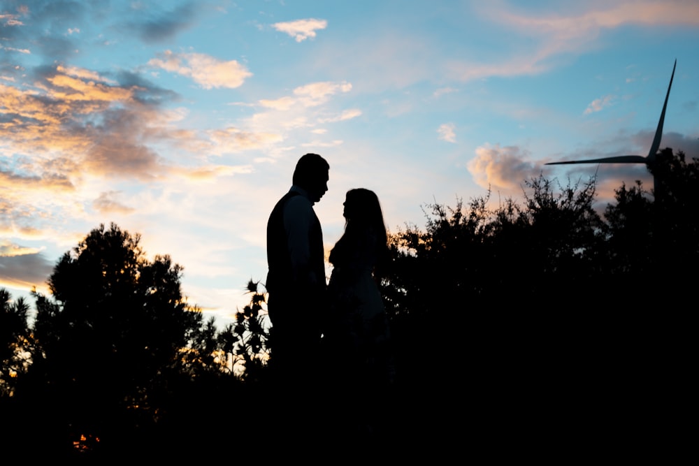 a man and a woman standing in front of a sunset