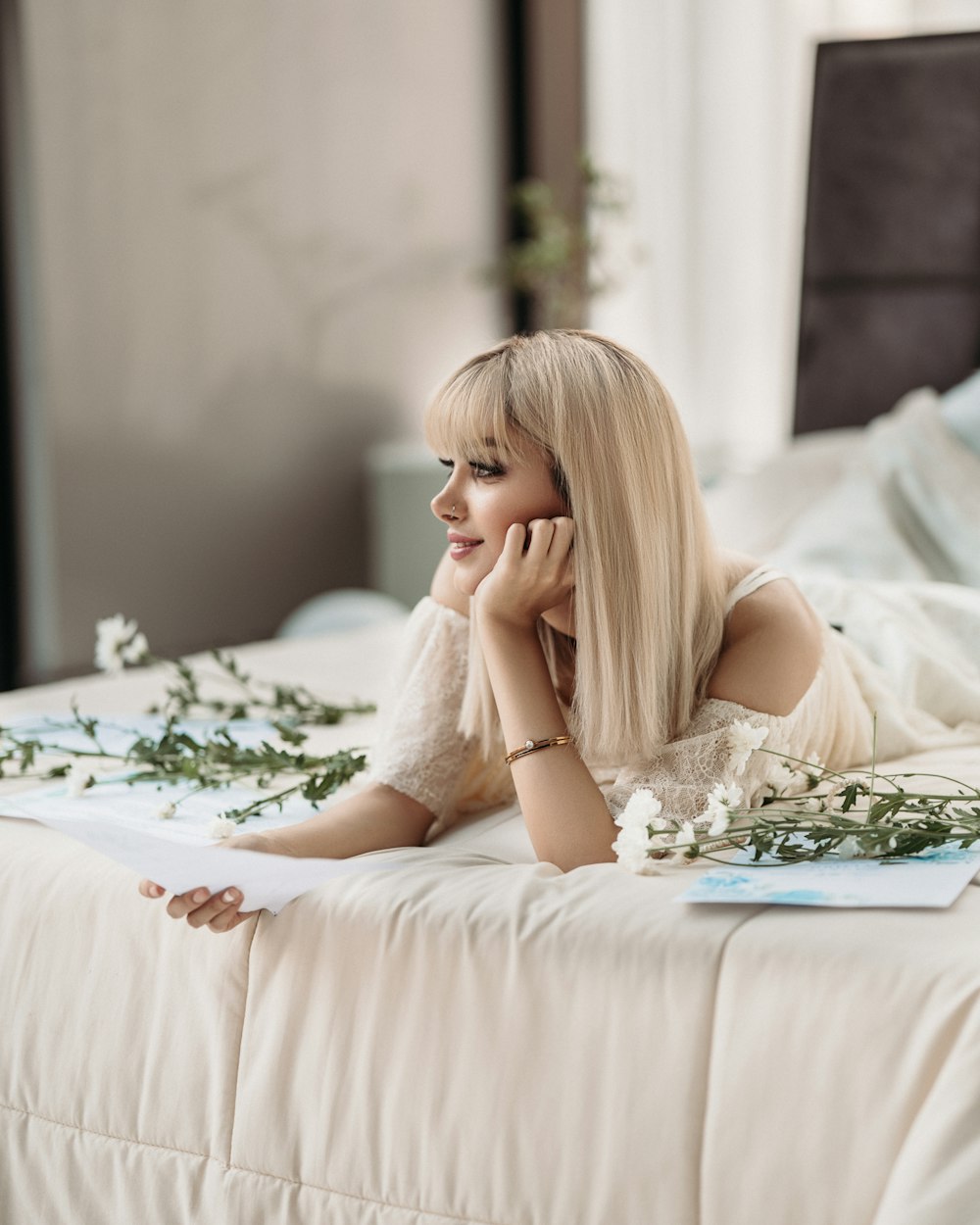 Una mujer acostada encima de una cama junto a flores
