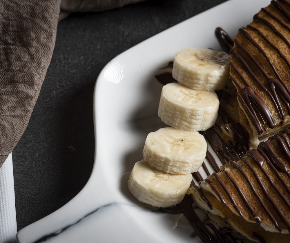 a white plate topped with banana slices and chocolate