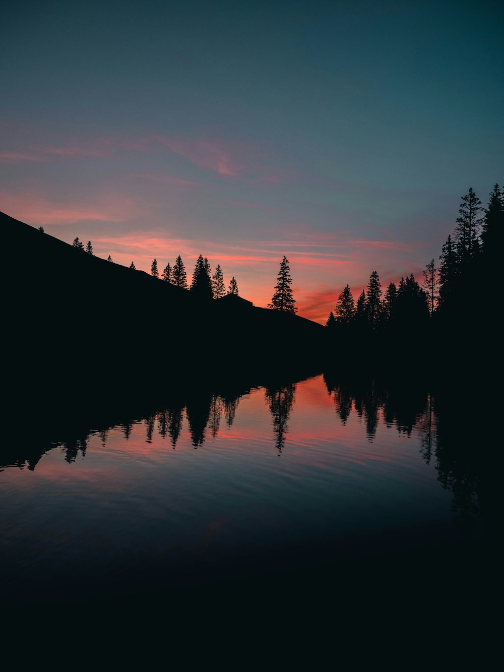 Die Sonne geht über einem See mit Bäumen im Hintergrund unter