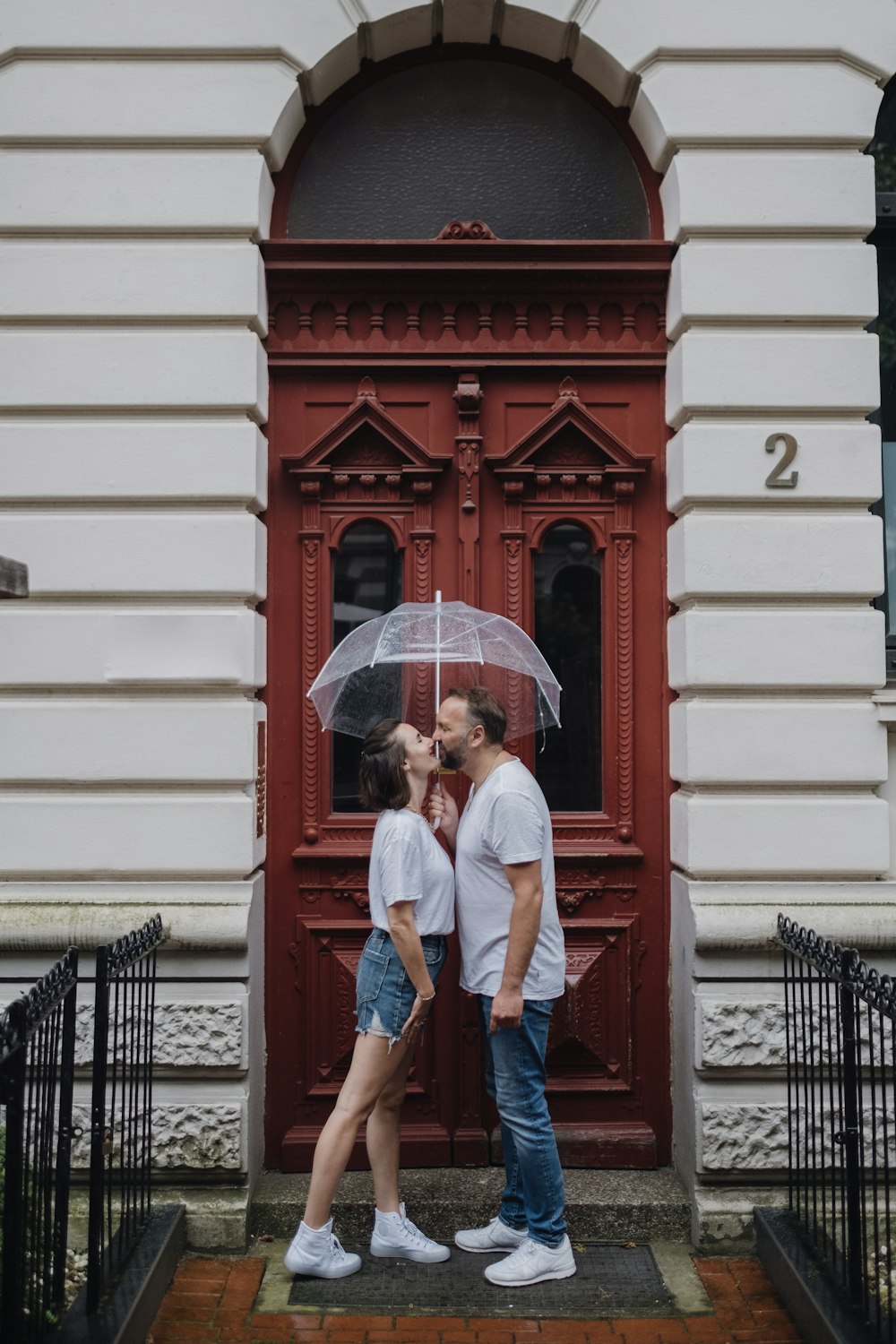 a couple kissing under an umbrella in front of a building