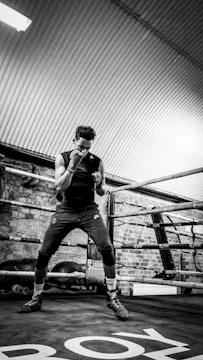 a man standing in a boxing ring talking on a cell phone