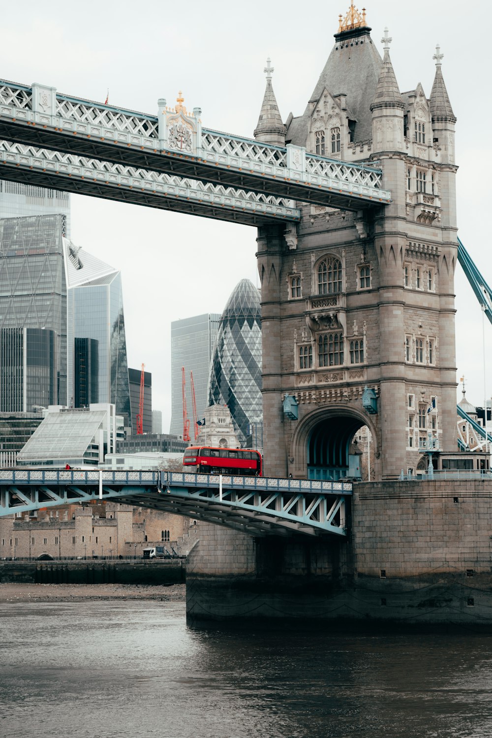 a red bus driving across a bridge over a river