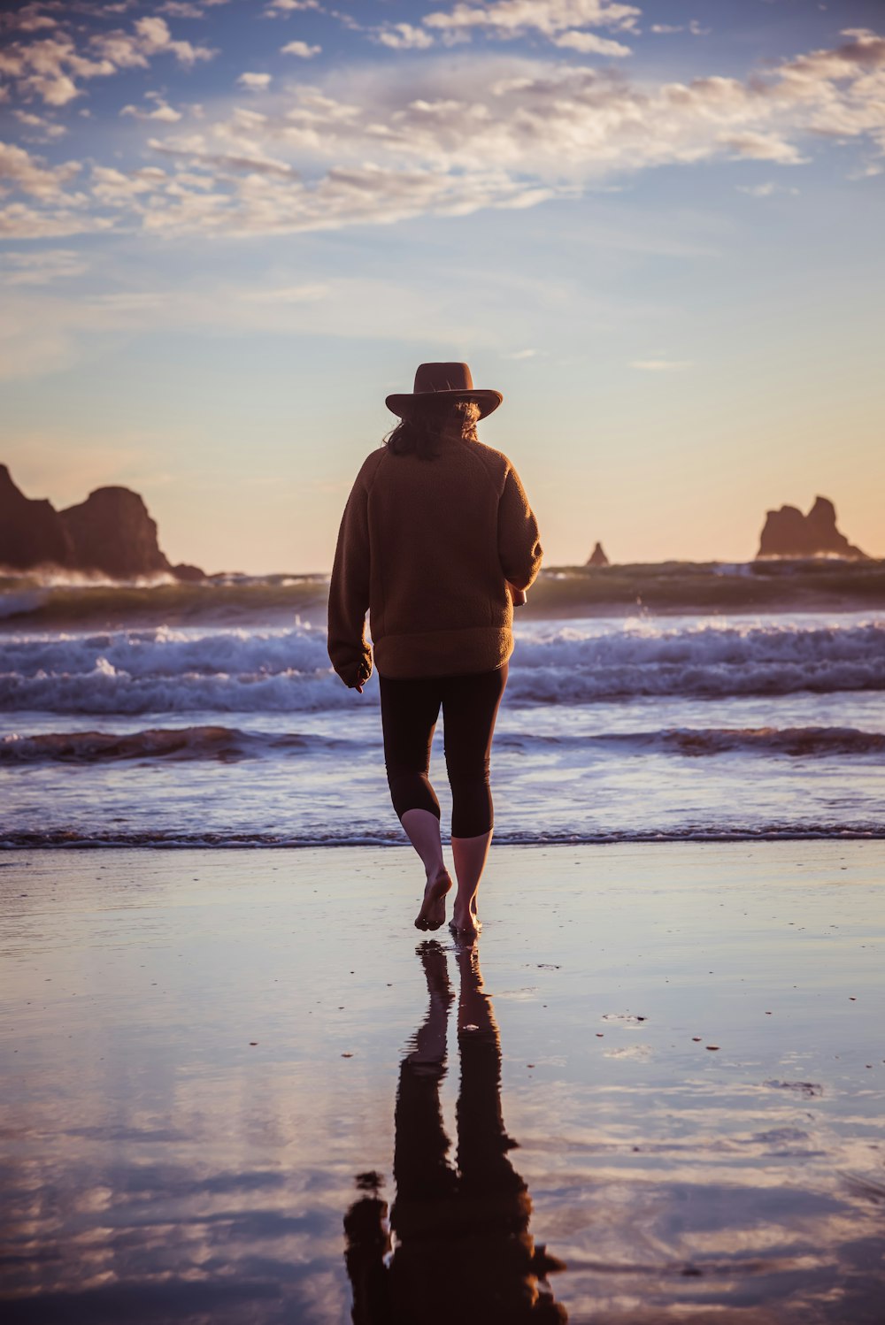 a man in a hat walks along the beach