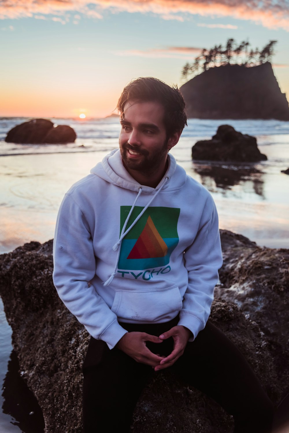 a man sitting on top of a rock near the ocean