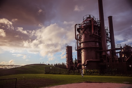 a large metal plant sitting on top of a lush green field