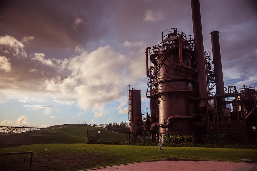 a large metal plant sitting on top of a lush green field