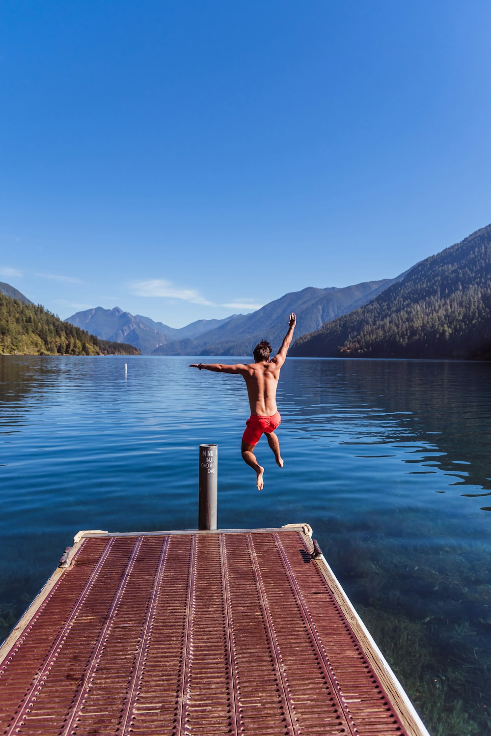 a man jumping off a dock into a lake