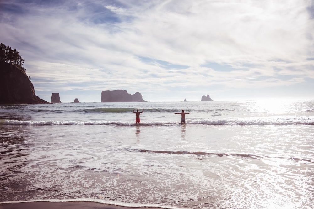 two people are standing in the water at the beach