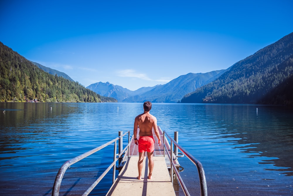 a man standing on a dock looking out over a lake