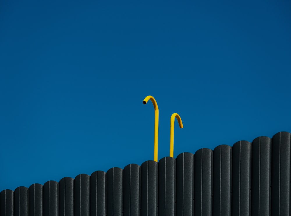 two yellow street lights on top of a black fence