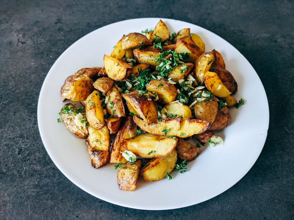 un plato blanco cubierto con patatas y perejil