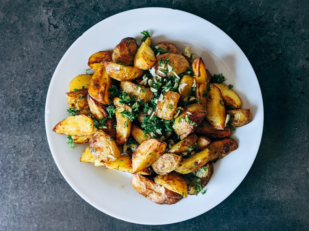 une assiette blanche garnie de pommes de terre et de légumes verts